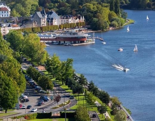 Sailing boats on the lake at Vichy, with a tree-lined avenue along the bank and villas among the trees.